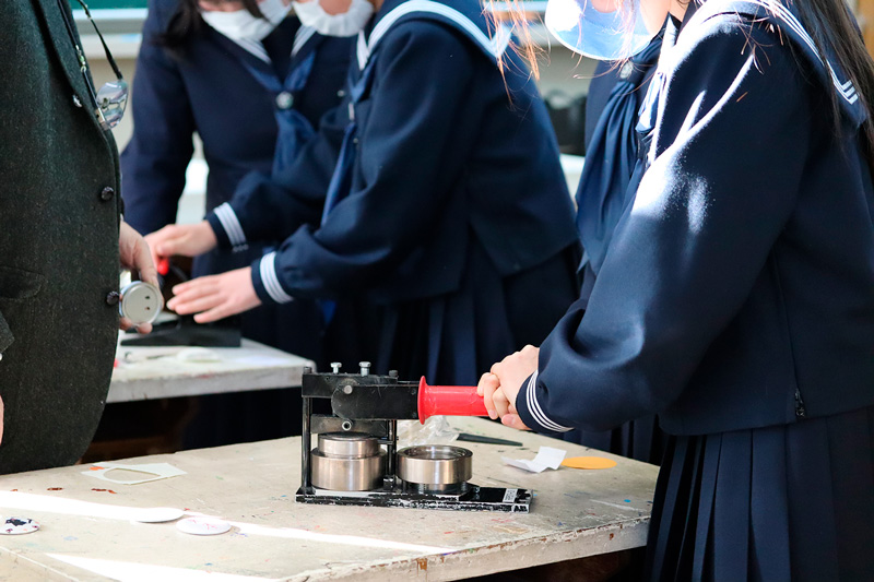缶バッジマシンで缶バッジを作る学生